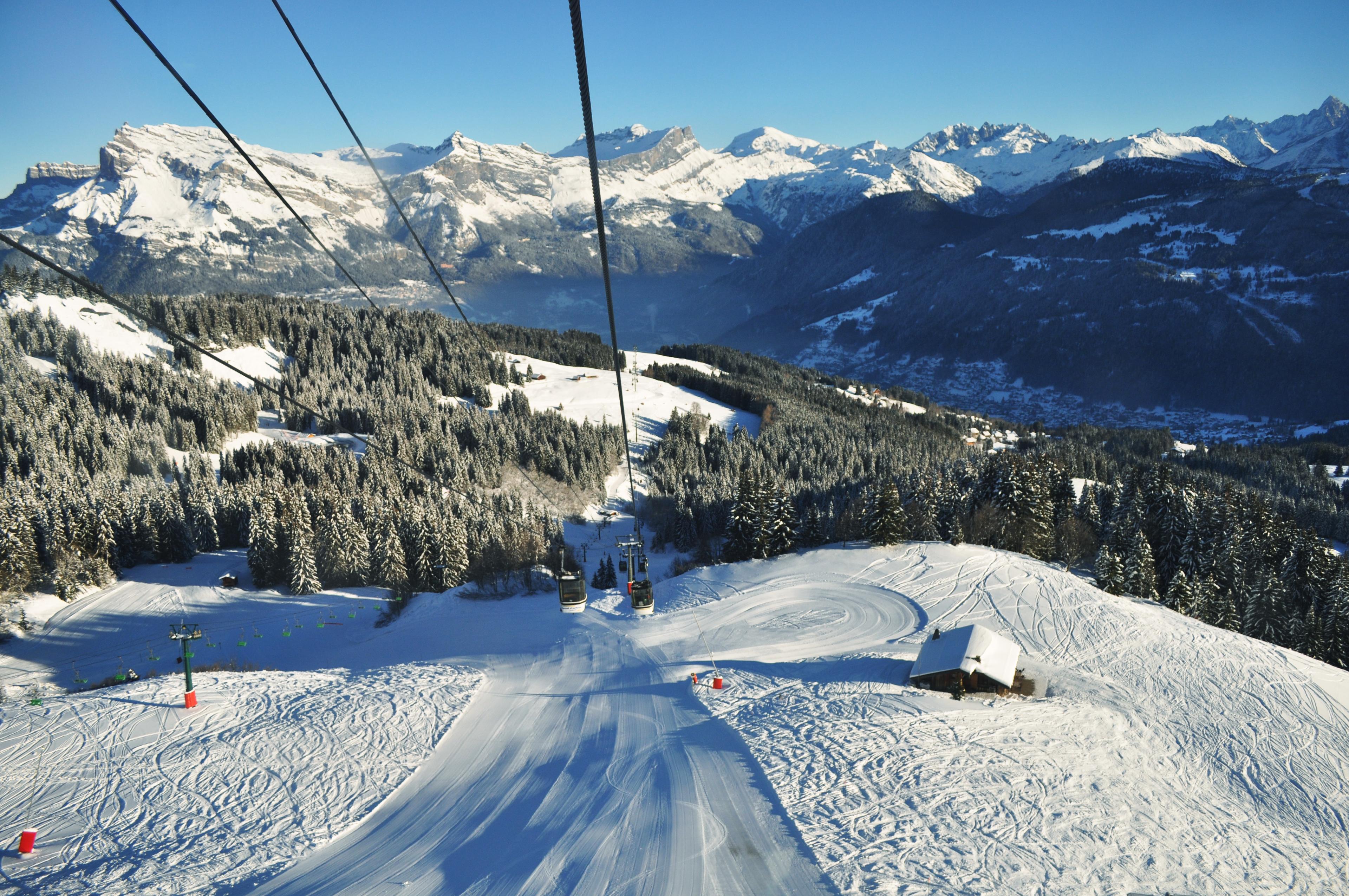 Gondola transporting skiiers to top of mountain above empty ski slope